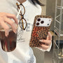 Glossy petite leopard phone case with delicate amber and espresso-brown patterning displayed flat against a warm neutral background.