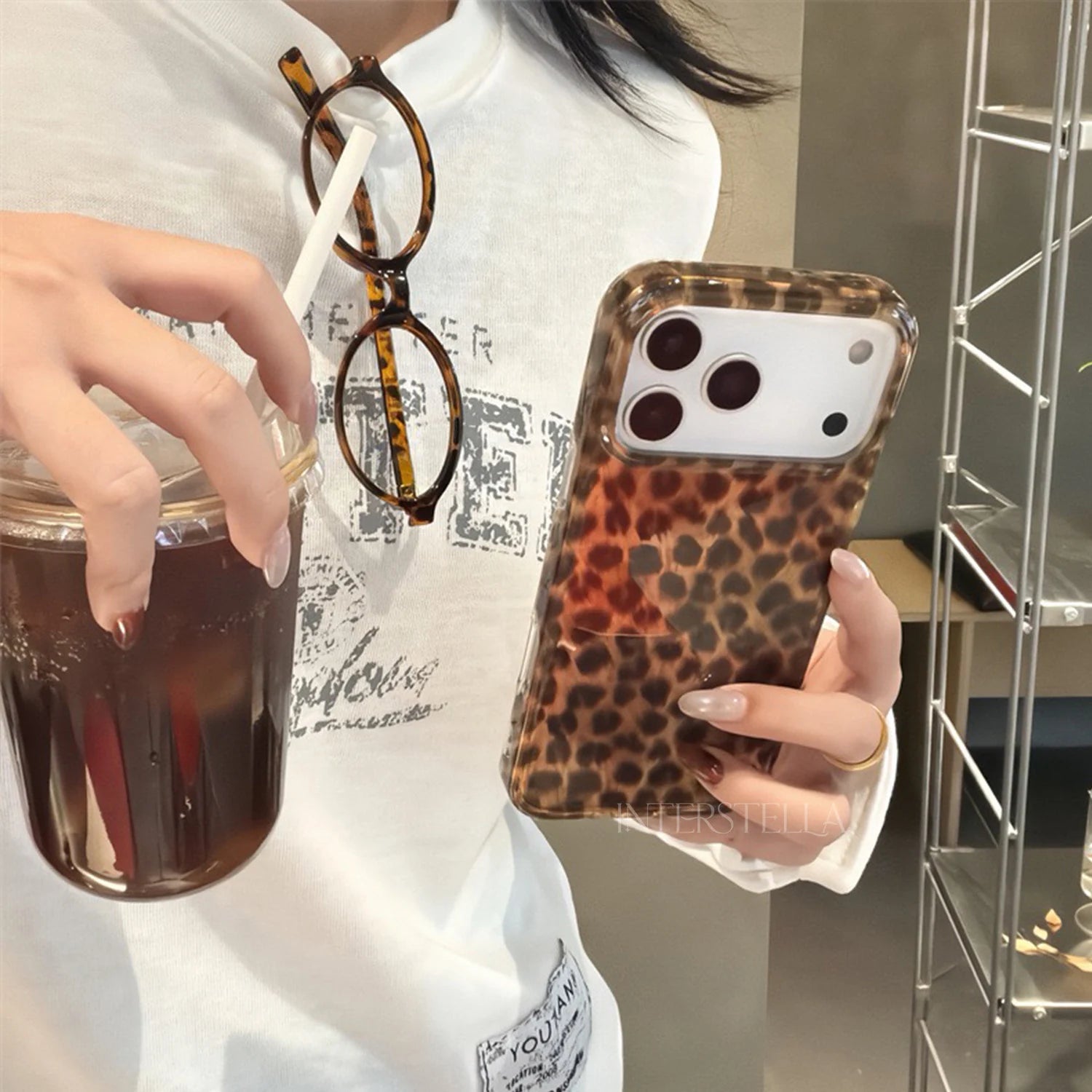 Glossy petite leopard phone case with delicate amber and espresso-brown patterning displayed flat against a warm neutral background.