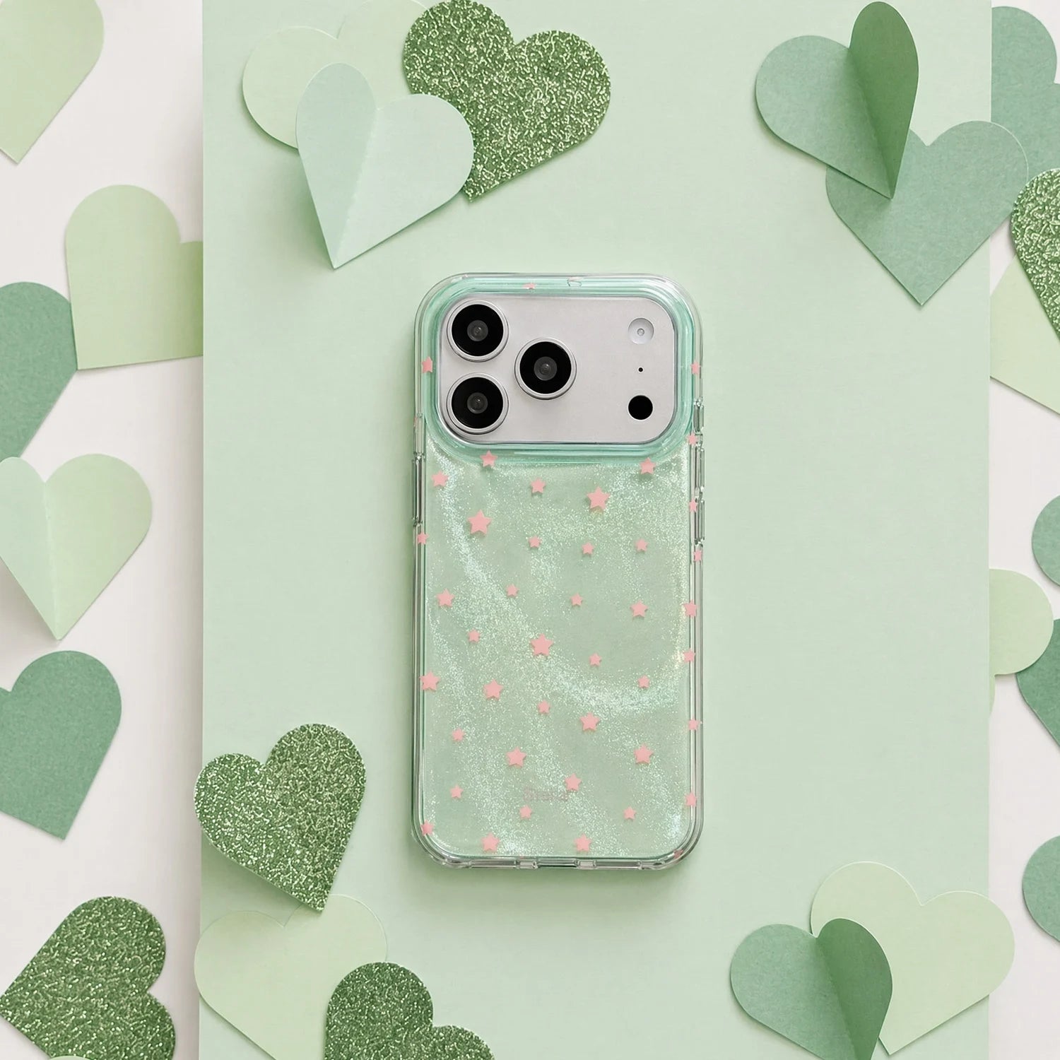 Mint green shimmering star phone case with pink stars on a soft green heart-themed background