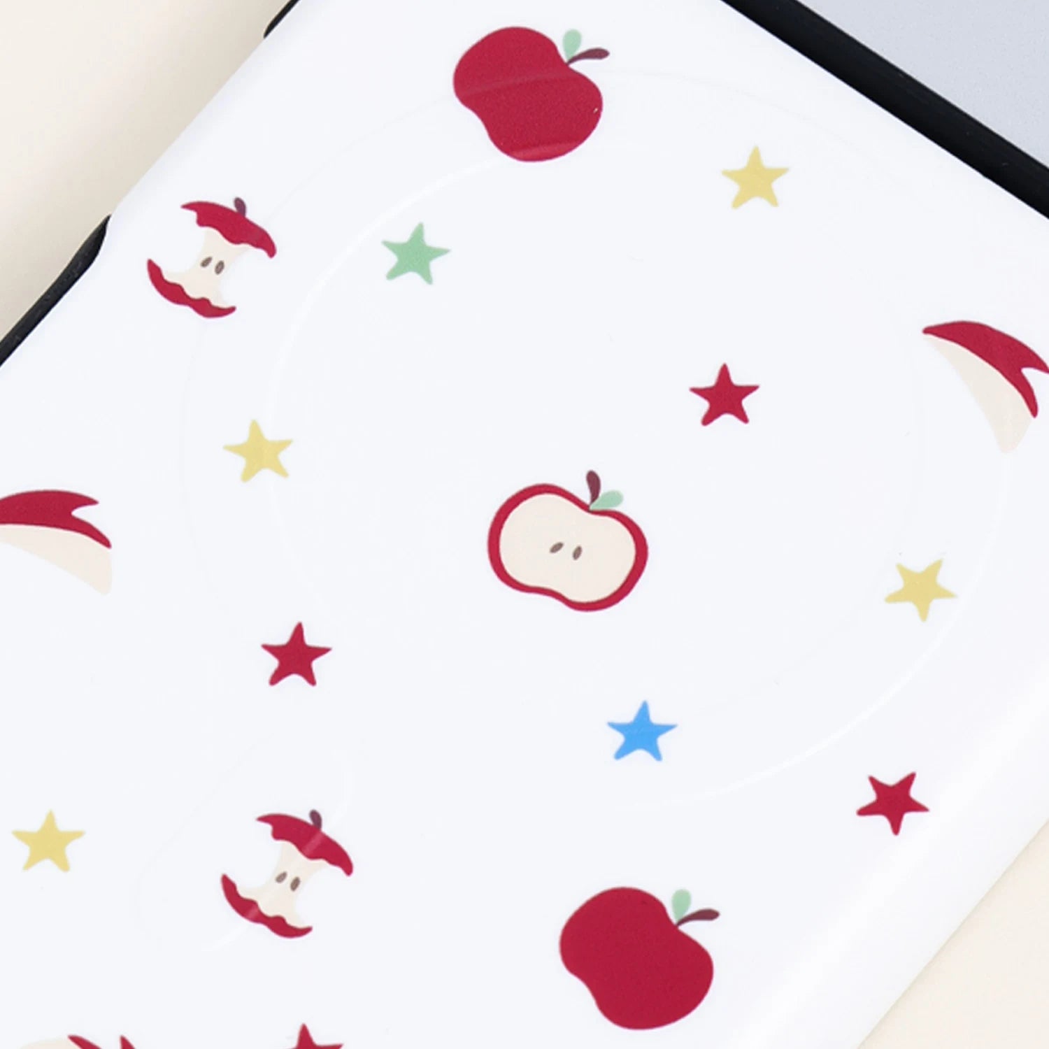 Detailed close-up of a white apple pattern phone case featuring small red apples, apple slices, and colorful star accents on a smooth printed surface.