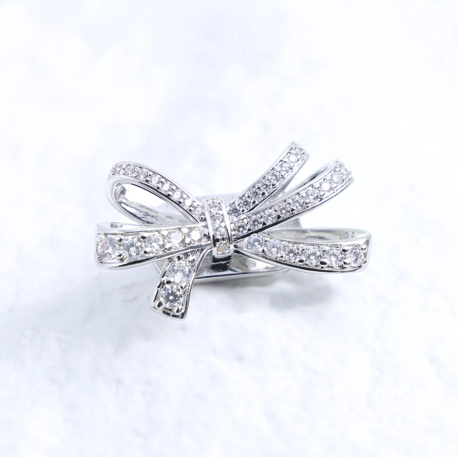 Crystal butterfly ribbon ear charm with Swarovski detailing and silver-tone finish on a white textured surface