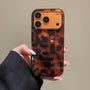 Front-facing hand-held view of a tortoiseshell leopard phone case with oversized spots and structured camera frame