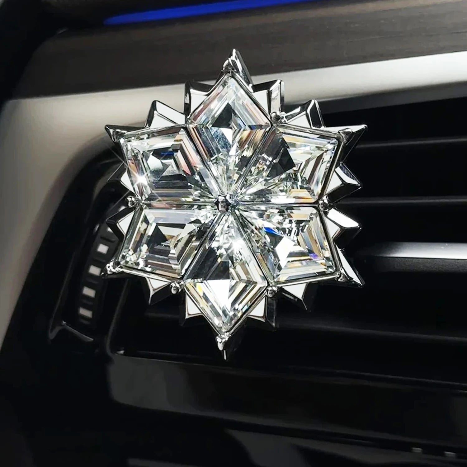 Snowflake-shaped crystal car air freshener clipped onto a car air vent