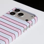 Close-up of Interstella pink striped phone case showing raised camera surround and side button cutouts