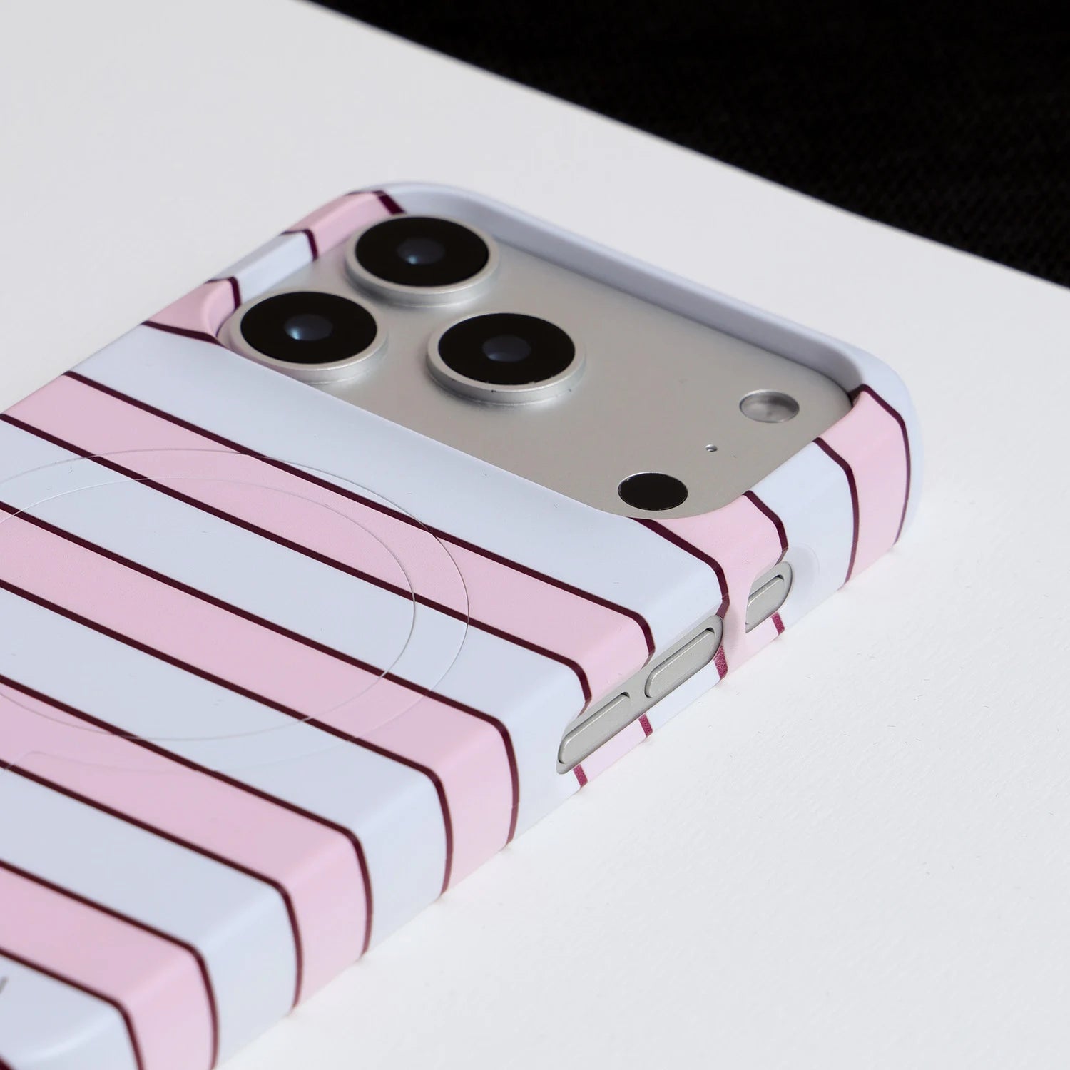Close-up of Interstella pink striped phone case showing raised camera surround and side button cutouts