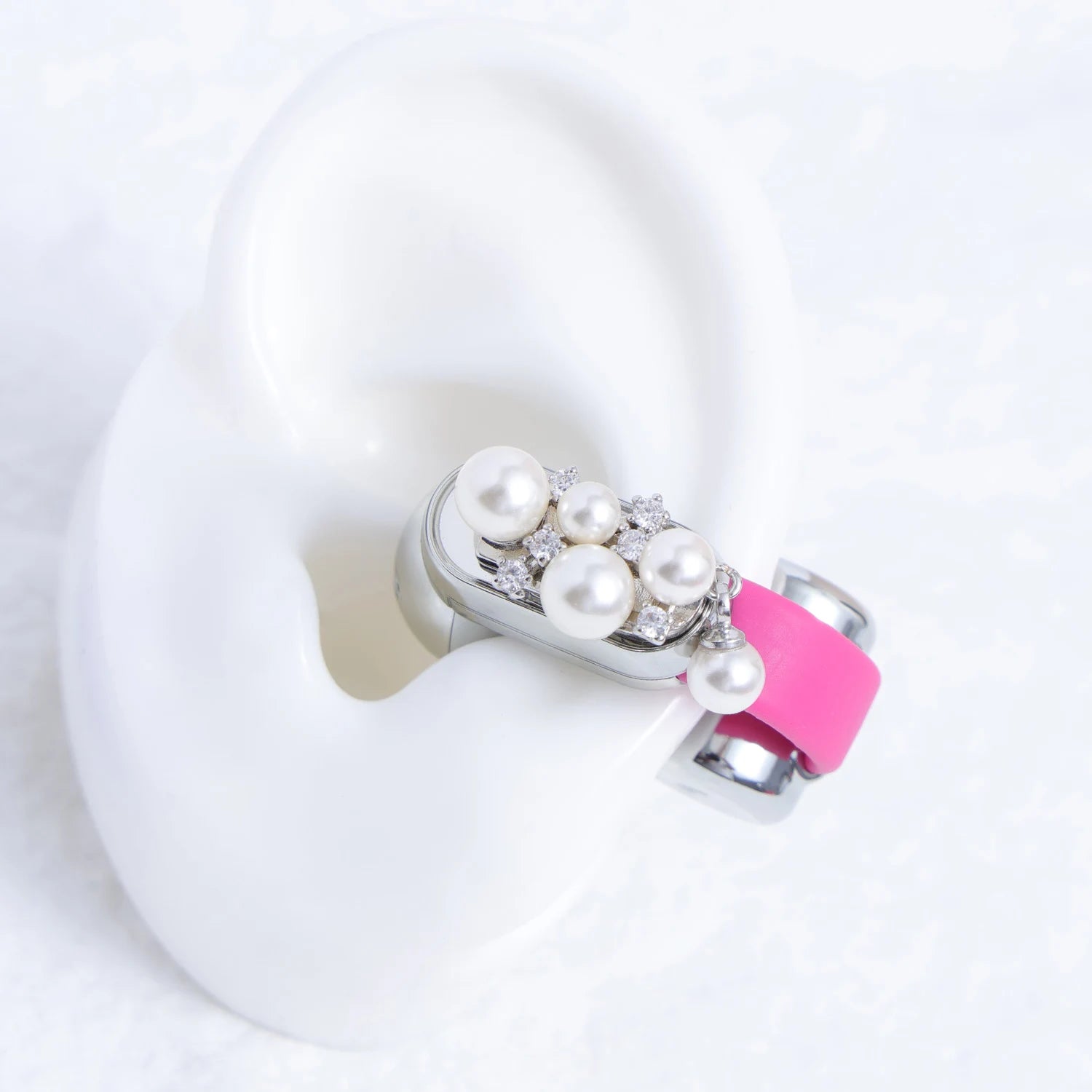 Pearl and Swarovski crystal ear charm attached to a pink Interstella Aura earbud and displayed on a white ear model.