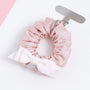 Blush pink fabric phone hanging ring shown flat with metal attachment tab, soft gathered folds, and an ivory bow accent.