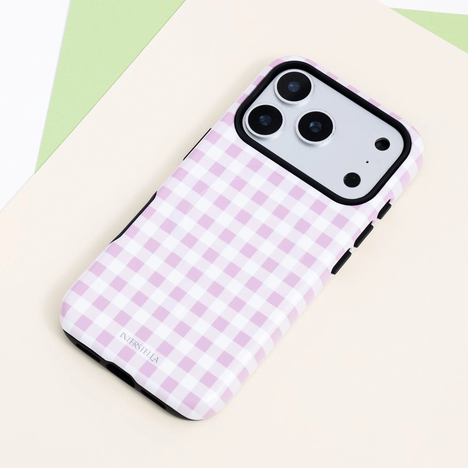 Blush gingham dual-layer phone case with a soft pink and white check pattern, black side buttons, and raised black camera surround.