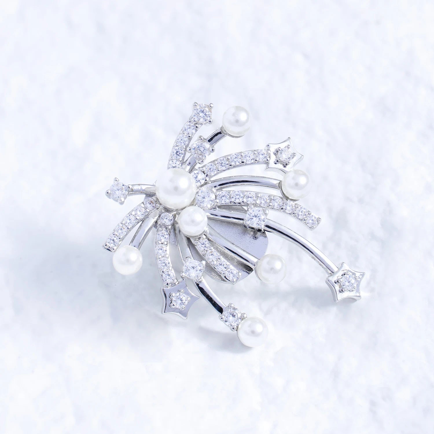 Pearl and crystal starfall ear charm with silver-tone plated finish on a white textured surface