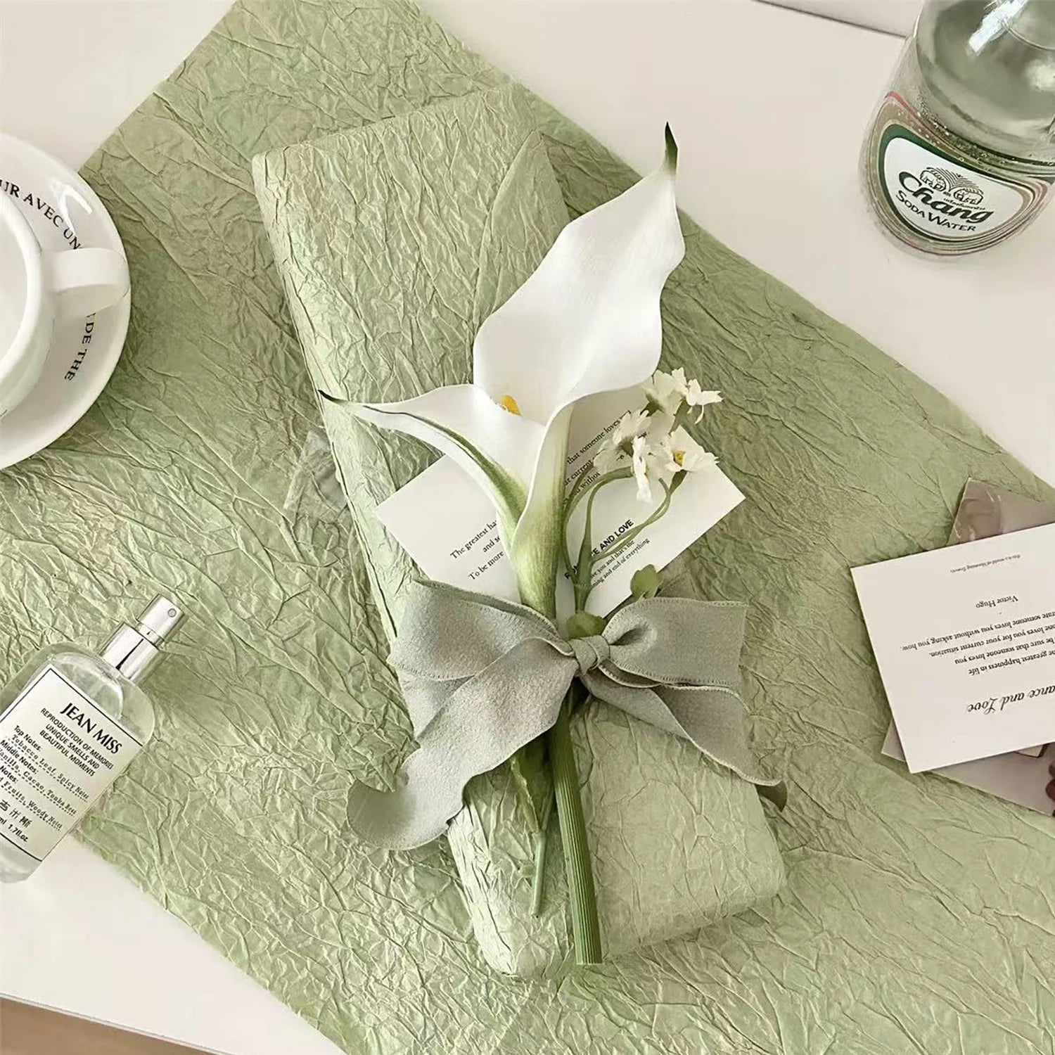 Sauge Orchidée floral gift wrapping style with orchid embellishment, ribbon accent, and soft botanical textured wrap