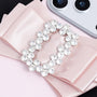 Detailed close-up of a handcrafted satin bow on a blush pink phone case, highlighting the rhinestone buckle and couture-inspired finish.