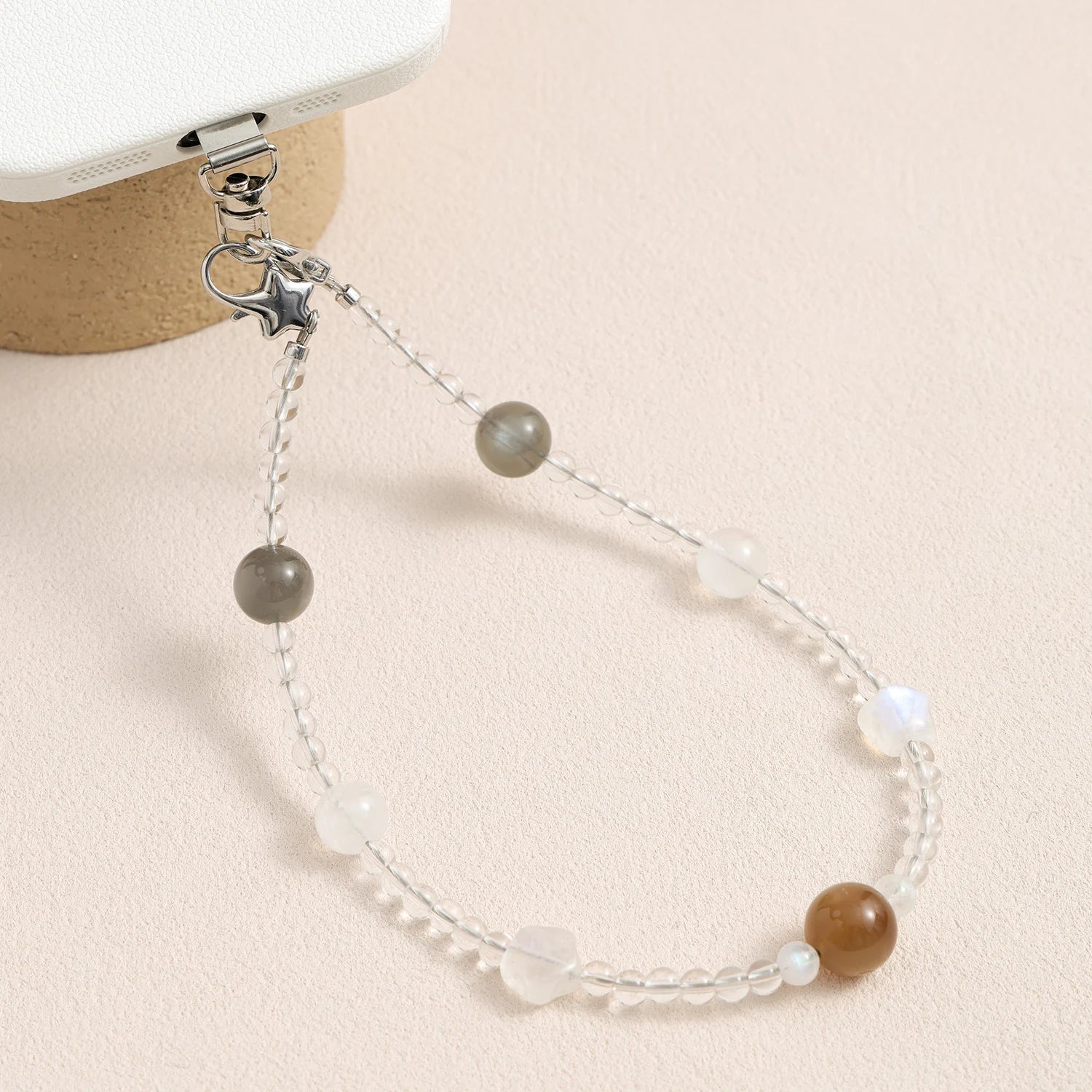 Grey moonstone, white quartz and peach moonstone gemstone phone strap with custom metal link clasp, handmade detachable bracelet phone strap on a neutral background.