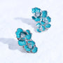 Close-up view of turquoise floral ear charm accessories with polished silver-tone metal and sparkling crystal details, styled as a pair.