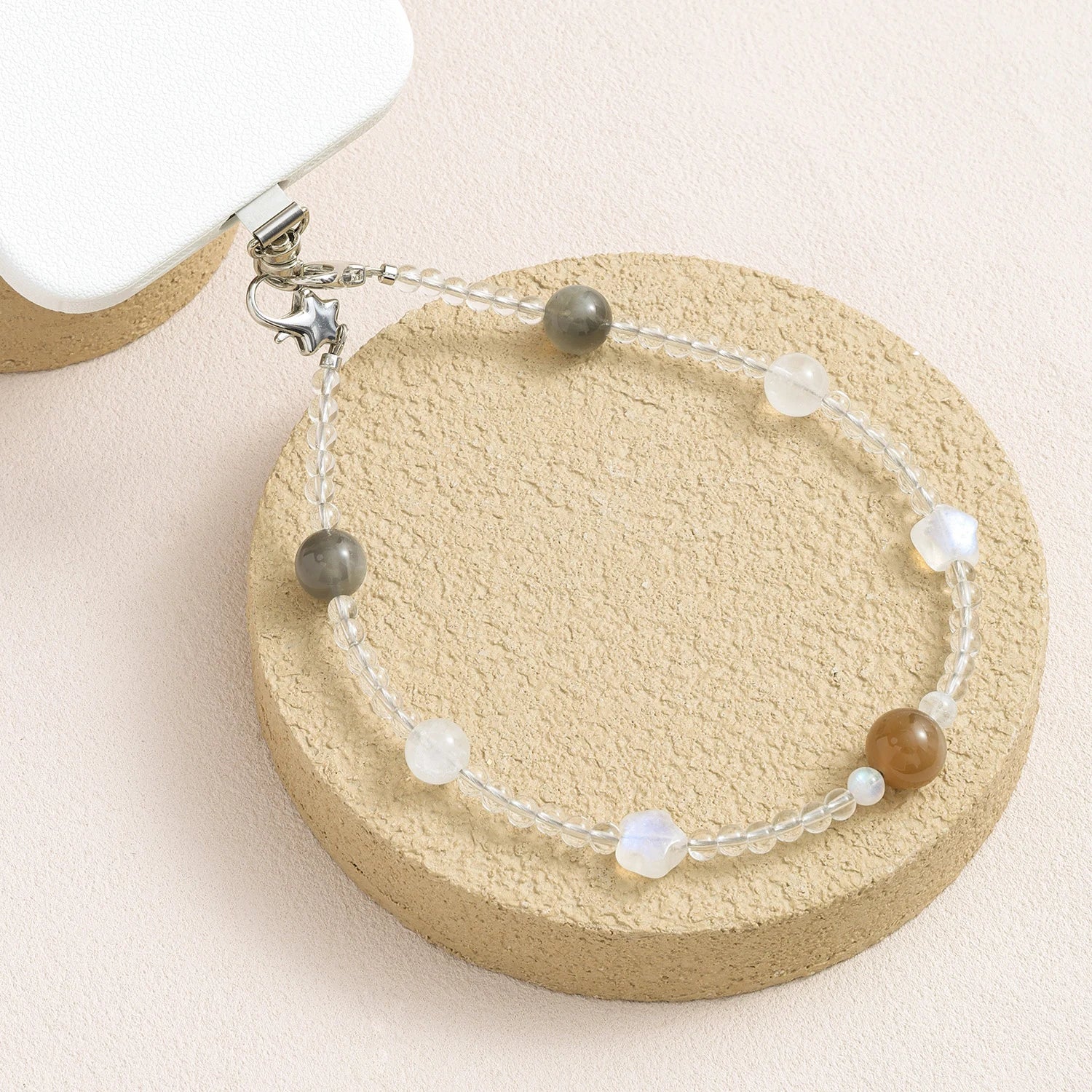 Grey moonstone, white quartz and peach moonstone gemstone phone strap with custom metal link clasp, handmade detachable bracelet phone strap on a neutral background.