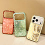 Three glossy star phone cases in red, mint green, and gold standing against a warm beige background