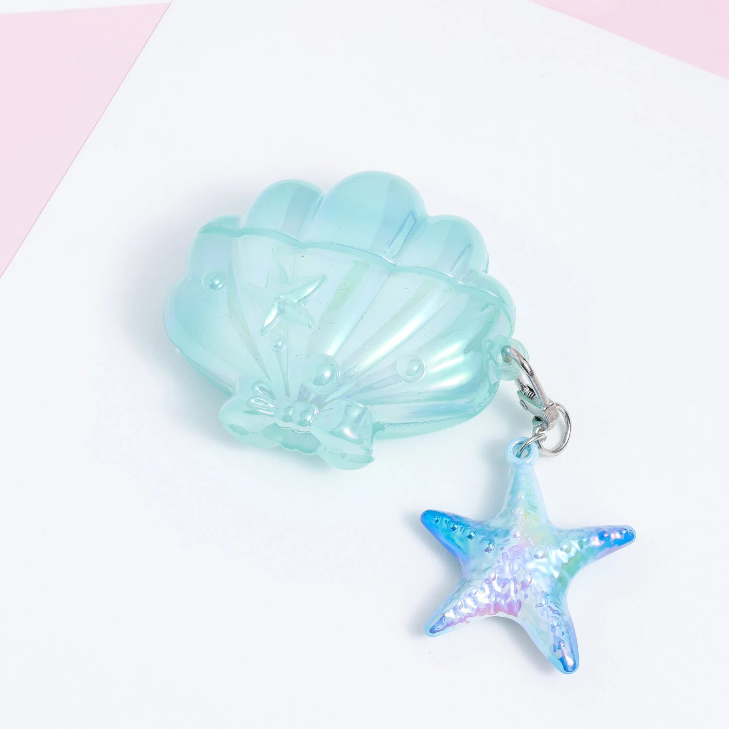 Closed aqua shell AirPods case with a glossy translucent surface and a dangling blue-iridescent starfish charm.