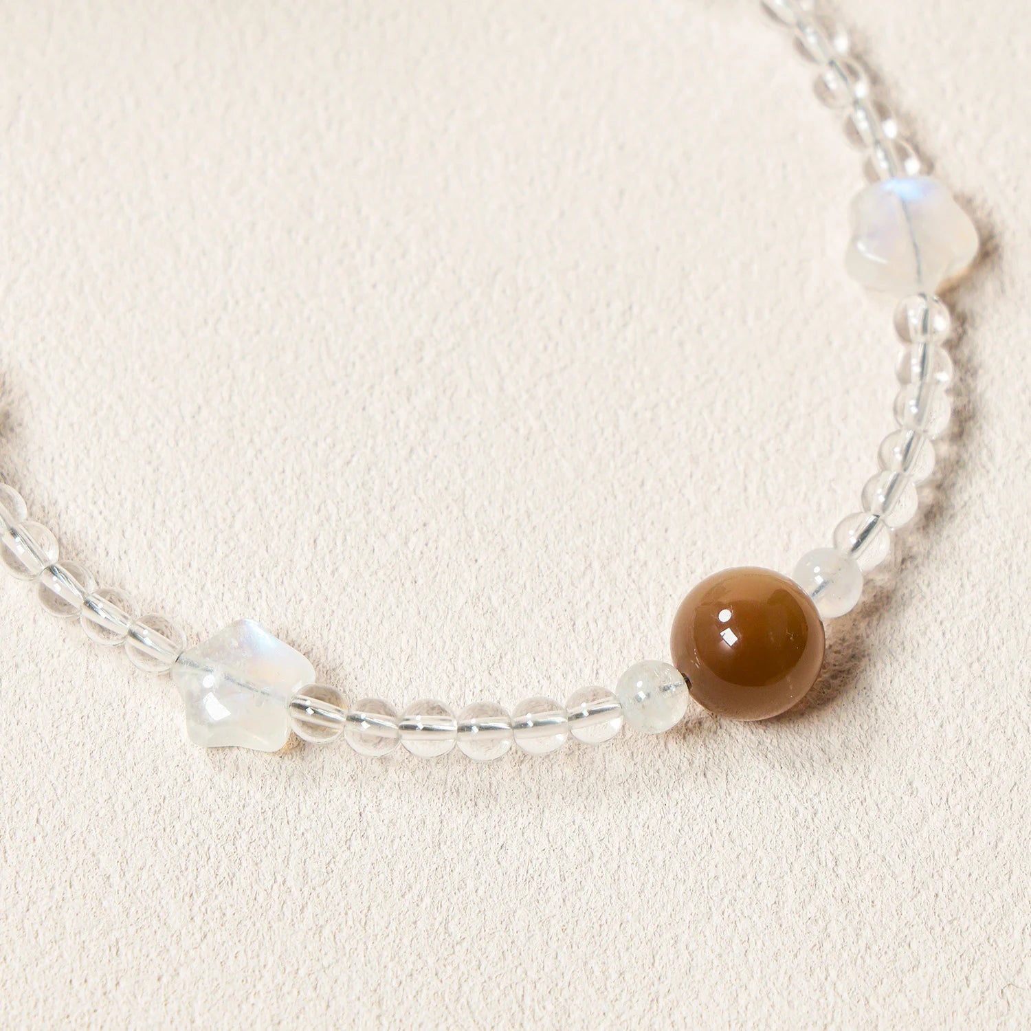 Grey moonstone, white quartz and peach moonstone gemstone phone strap with custom metal link clasp, handmade detachable bracelet phone strap on a neutral background.