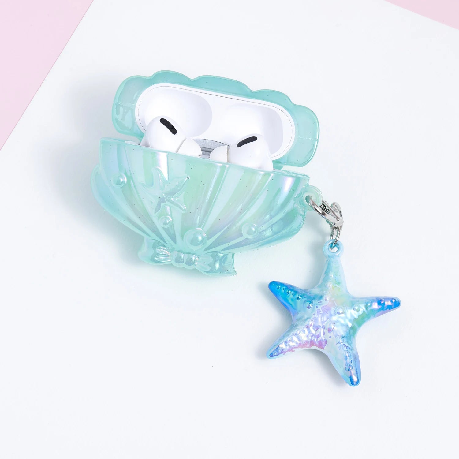 Open aqua shell-shaped AirPods case holding white AirPods, styled with pearl and starfish detailing and a dangling starfish charm.