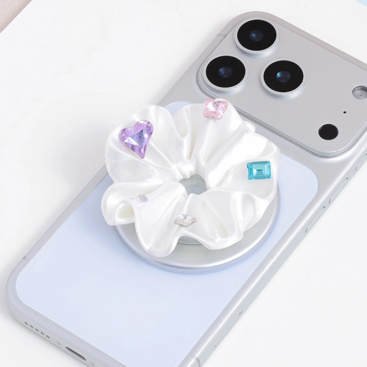 Close-up of a white 3D-printed jewel rosette phone grip stand with heart and faceted decorative accents on a silver base.