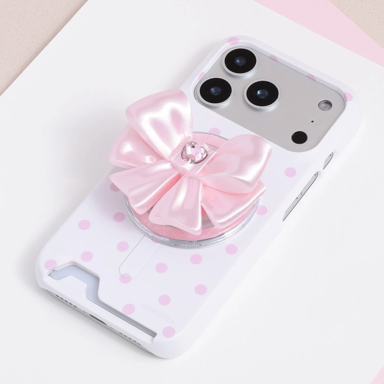 Blush pink jewel bow phone grip stand mounted on a pale pink polka dot phone case.