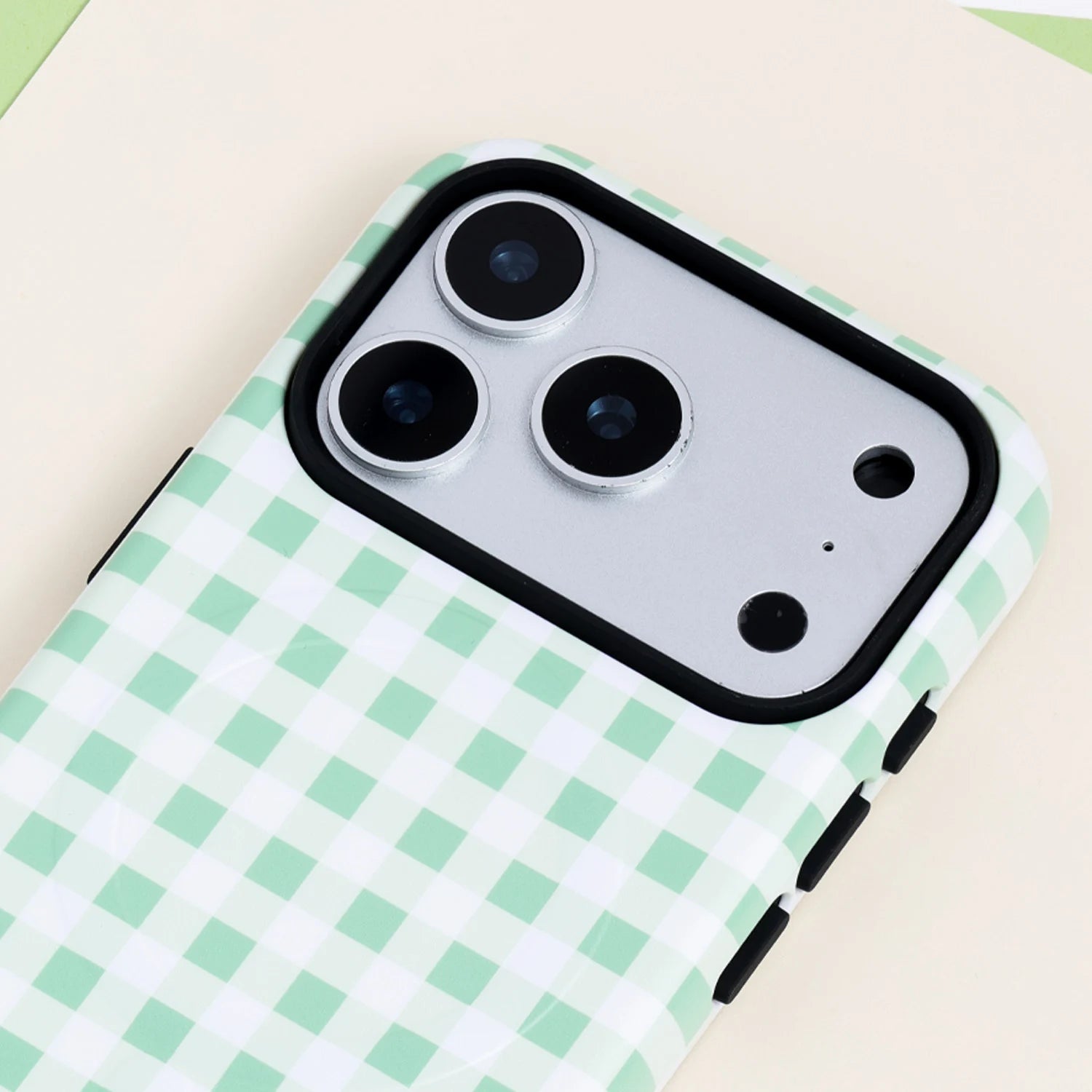Close-up of the Mint gingham phone case showing the pastel green check pattern, smooth film hard shell finish, and black raised camera edge.