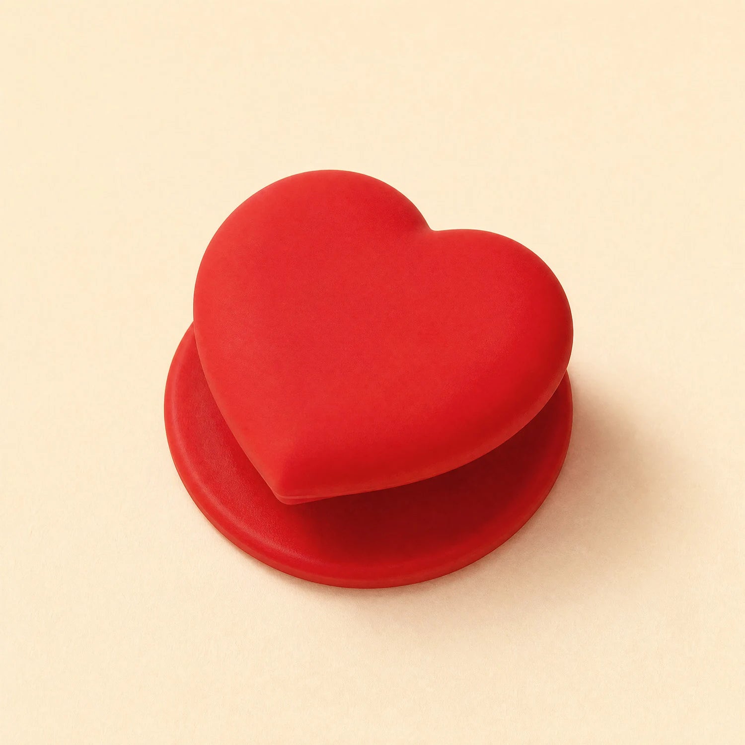 Scarlet red heart phone grip stand with a matching red round base displayed on a beige background.