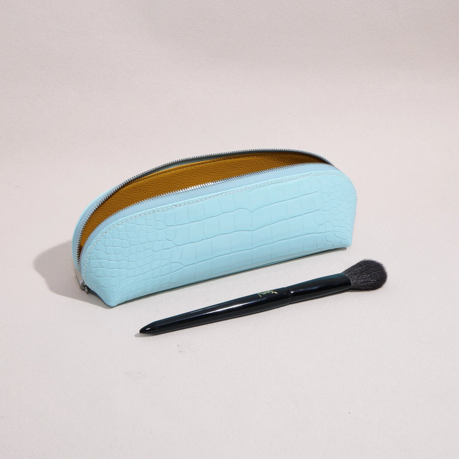 Open rectangular brow pencil pouch holding makeup brushes inside a structured leather case