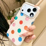Close-up of an ivory phone case with colorful painted dots held in hand
