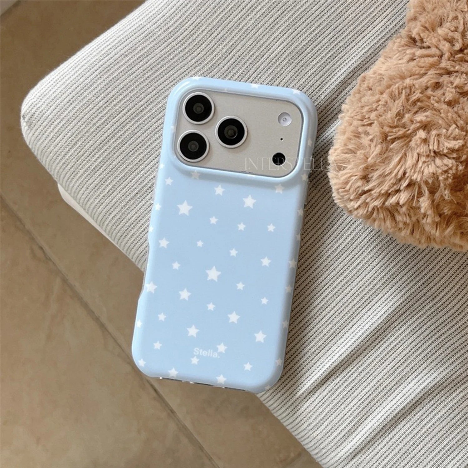 Baby blue matte star phone case with white star print resting on a sofa
