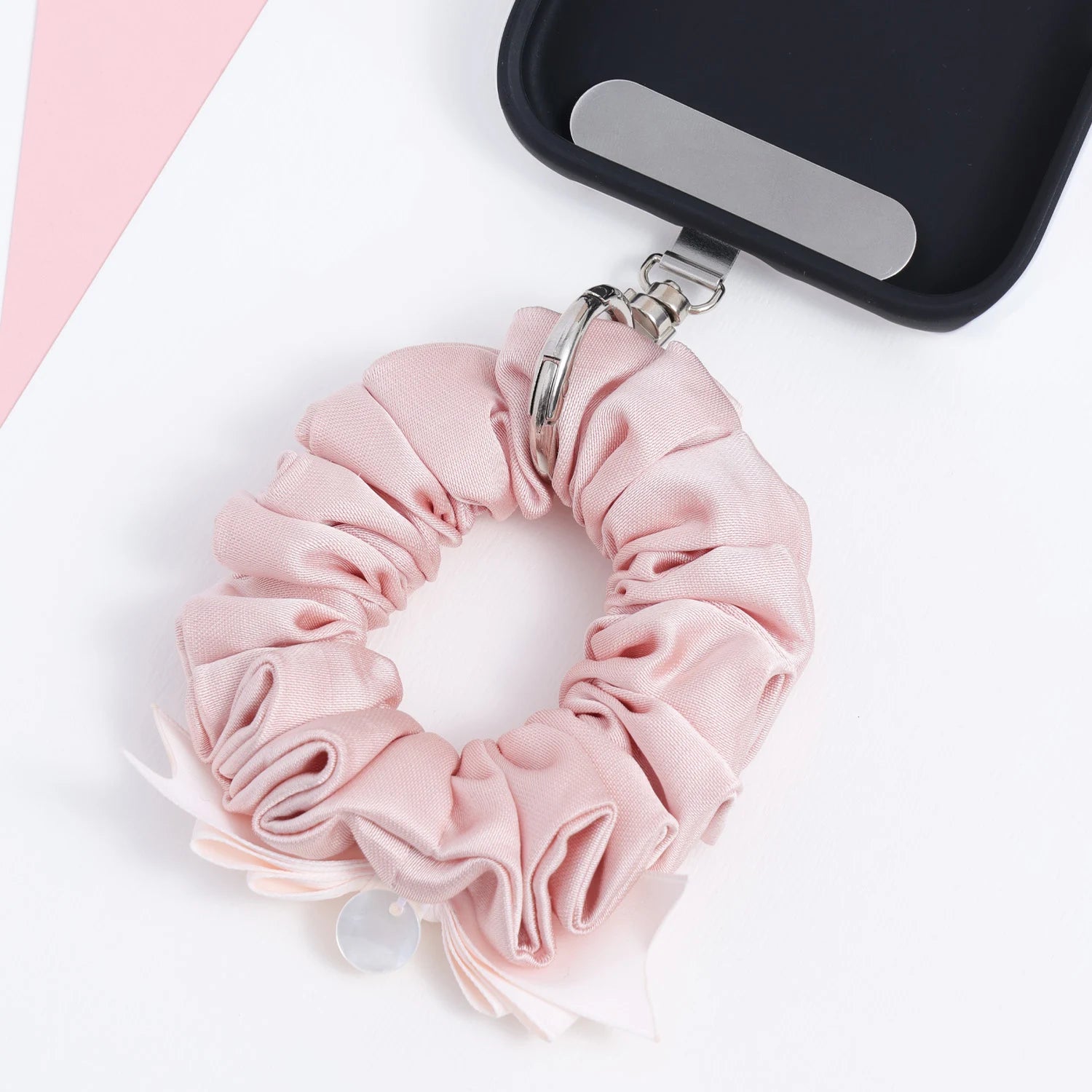 Close-up underside view of the blush pink phone hanging ring showing the gathered fabric construction, attached bow detail, and silver hardware connection.
