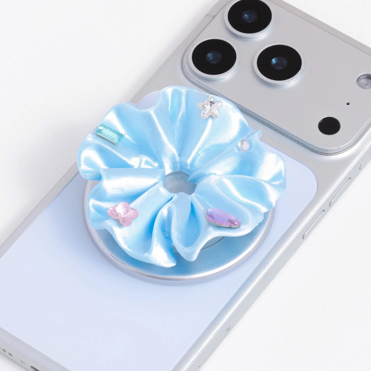 Close-up of a blue 3D-printed jewel rosette phone grip stand with pastel decorative accents on a silver base.