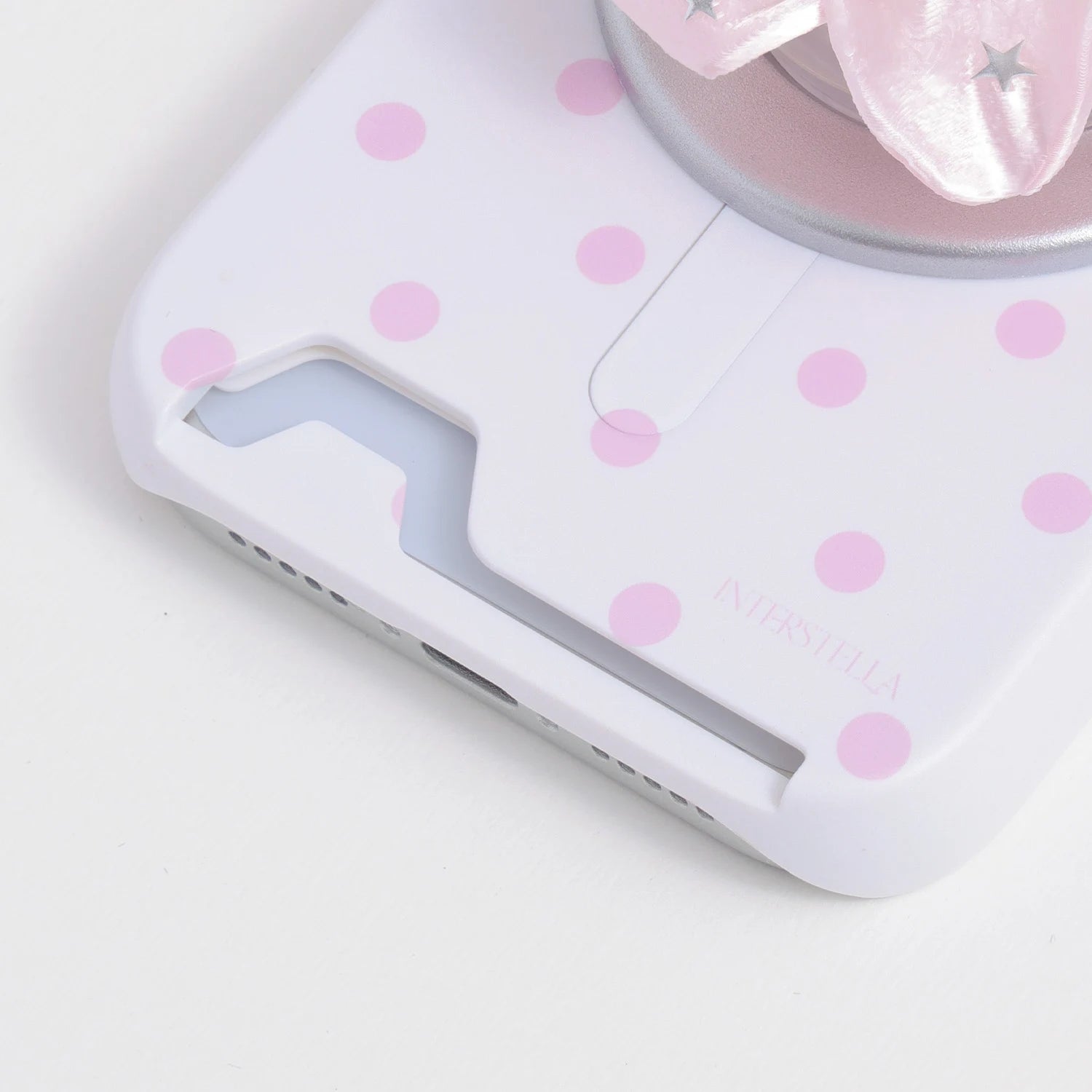 Close-up of the porcelain white oversized polka dot card phone case bottom section with card slot opening and blush-pink dots.