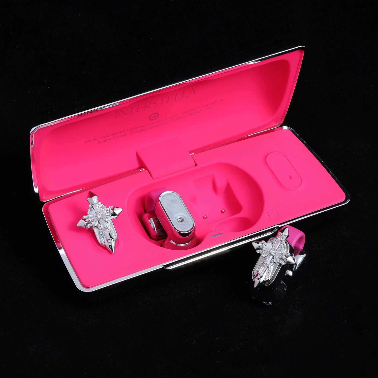 Silver-tone crystal cross ear charms displayed with pink Interstella magnetic earphone charging case