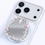 Close-up of the Relic Frame phone stand showing the irregular silver-toned border, mirror-like center, and pink crystal embellishments.