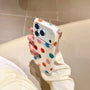 Three-quarter hand-held view of a painterly polka dot phone case with clear side frame
