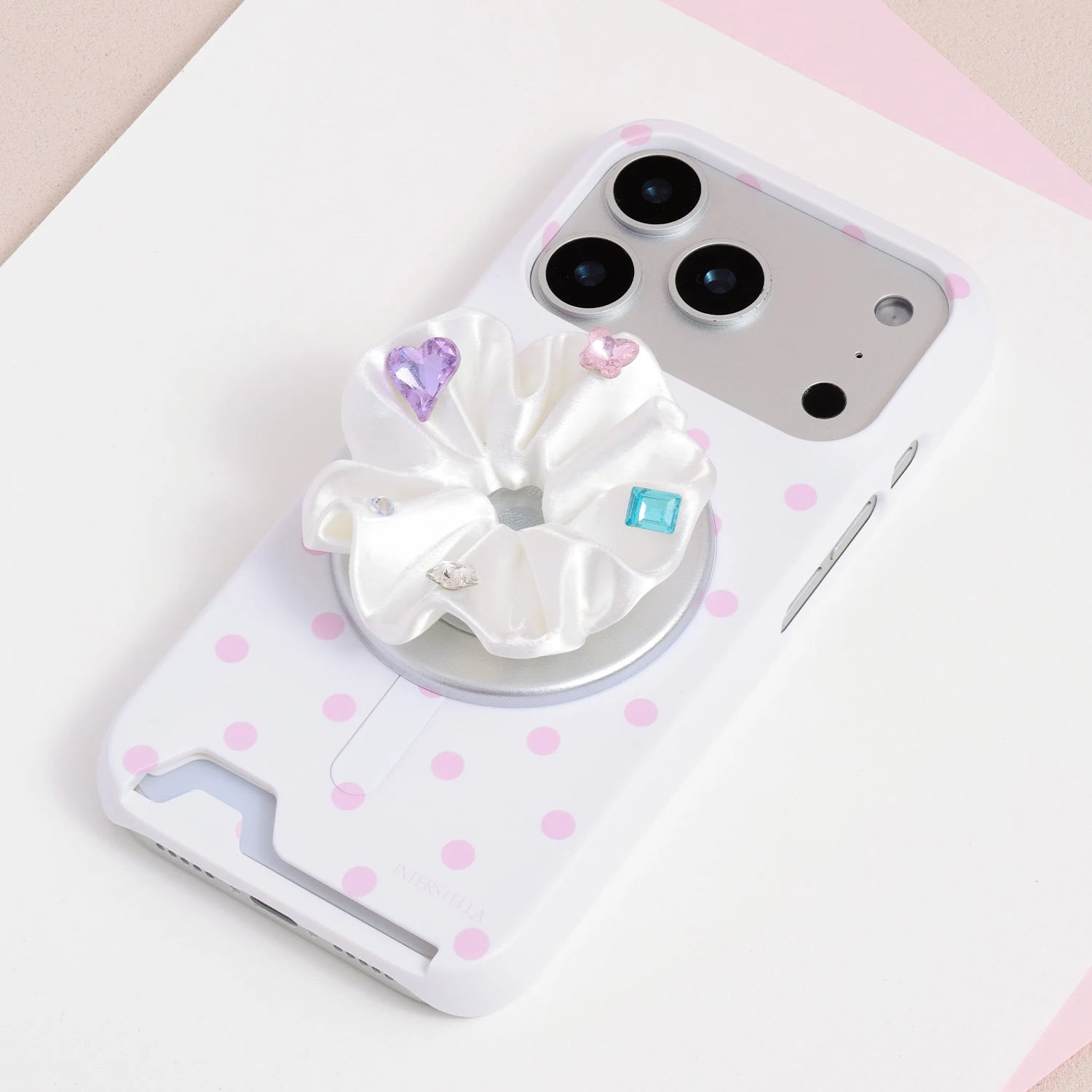 White jewel rosette phone grip stand attached to a white phone case with soft pink star print.