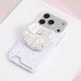 Ivory white jewel bow phone grip stand mounted on a white phone case with soft pink star print.