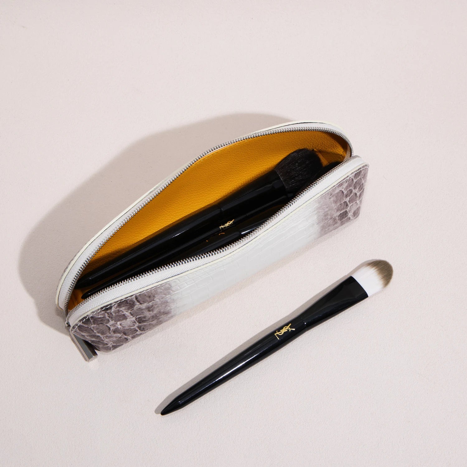 Open rectangular brow pencil pouch holding makeup brushes inside a structured leather case