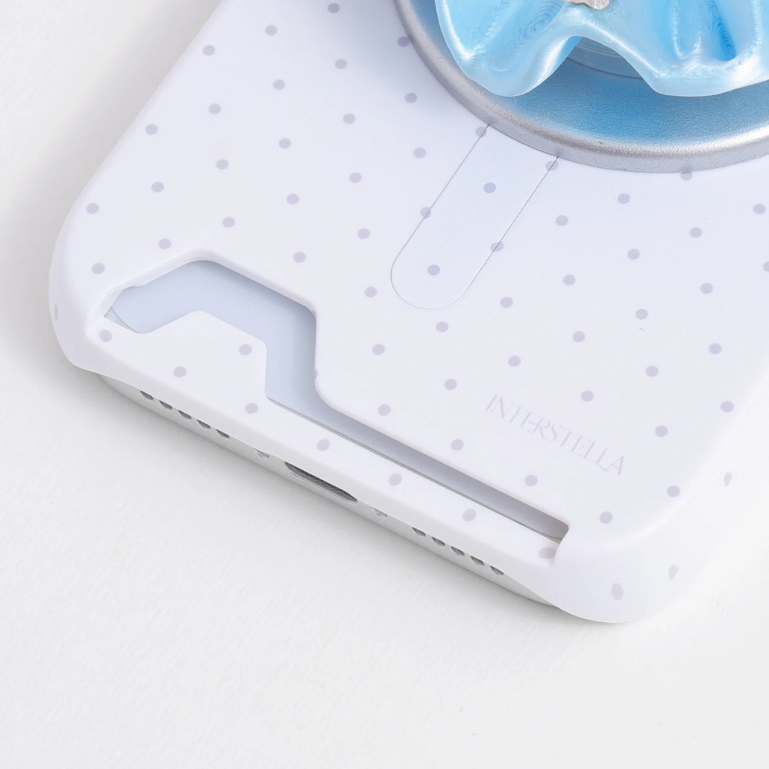 Close-up of the porcelain white pastel polka dot phone case showing the built-in card slot opening and subtle dotted pattern.