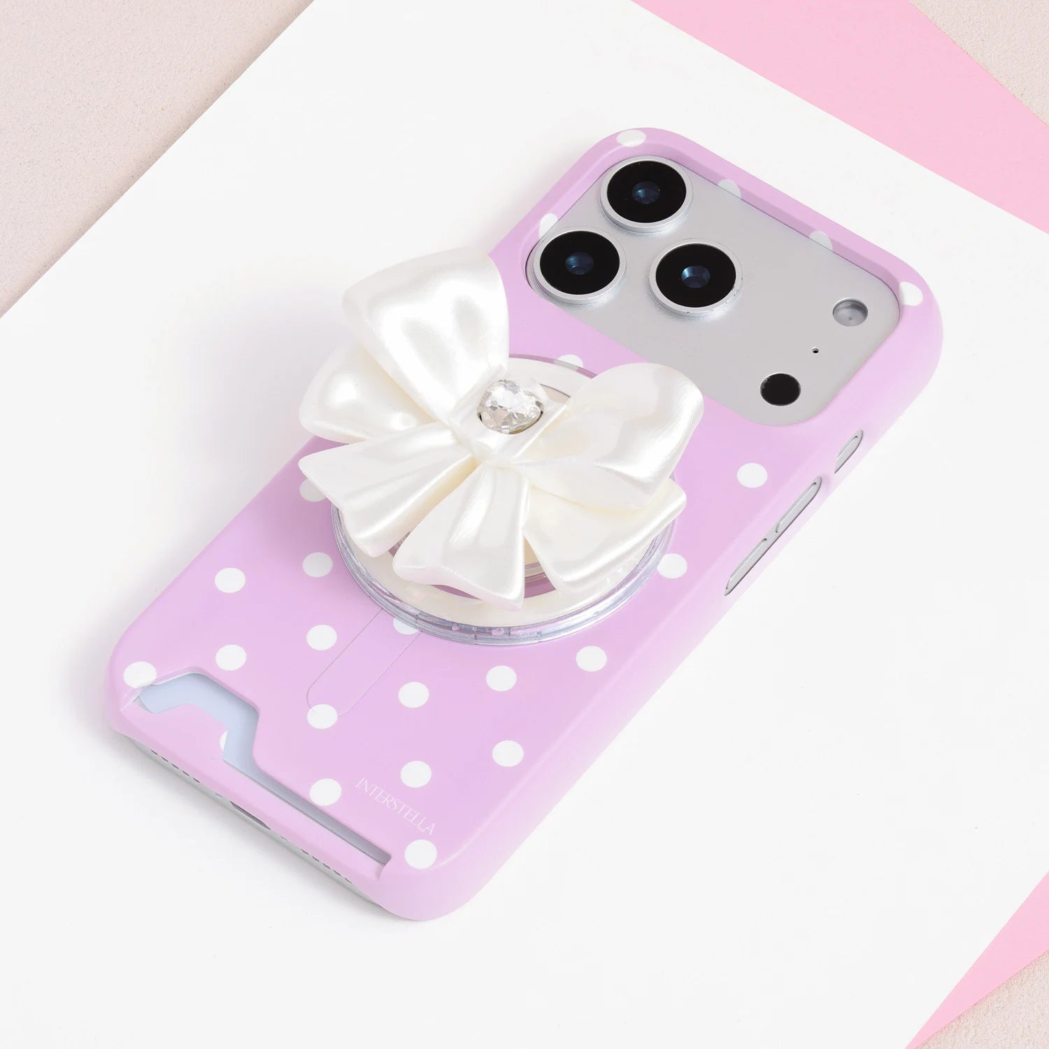 Ivory jewel bow phone grip stand attached to a pink polka dot phone case.