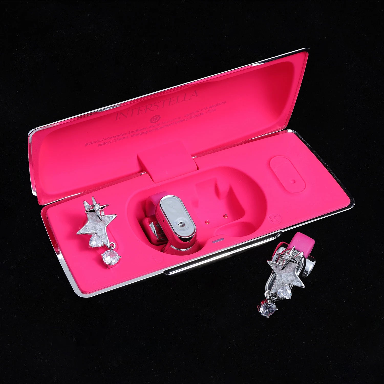 Silver-tone star ear charms with clear crystal drop displayed with pink Interstella magnetic earphone charging case