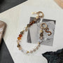 Handcrafted crystal and freshwater pearl phone strap with mixed metal accents and decorative clasp